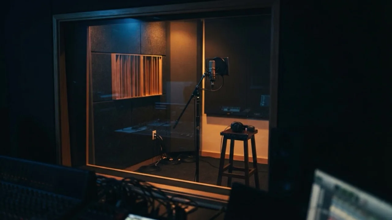 Empty recording studio booth with a microphone under warm lights
